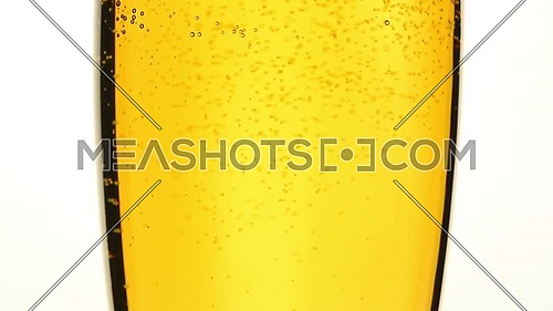 Close up background of pouring beer, sparkling wine or champagne with bubbles in glass, low angle side view, slow motion