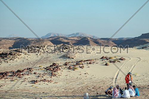 Group of tourists sitting with bedouin guides exploring Sinai Trail from Ain Hodouda by day.