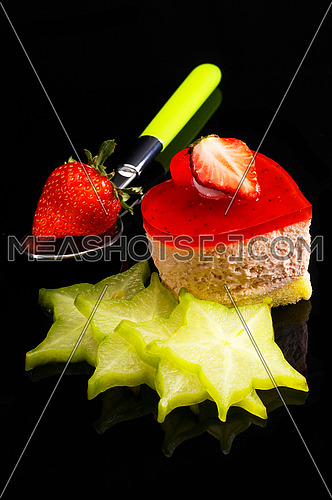 heart shaped strawberry cake dith star fruit or carambola decoration over black reflective backgound