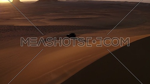Aerial shot for 4x4 Car moving through sand dunes in the desert at sunrise