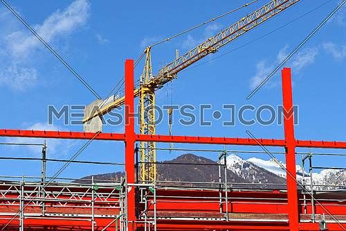 New steel beam construction being built with yellow crane against blue skies and white clouds