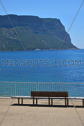 Sea shore esplanade recreation area with bench seats and mountains on horizon