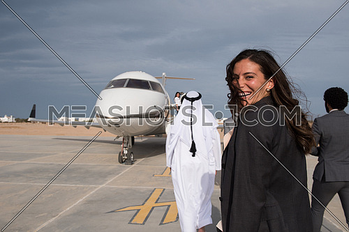 young successful middle eastern business woman walking with Arab business partner in front of private airplane