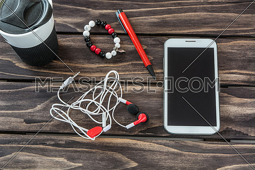 Still life with smart phone,headset,mug,pen and bracelet 