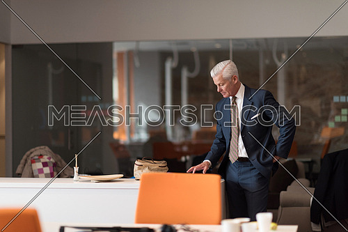 senior business man reading reports on tablet computer at modern office interior
