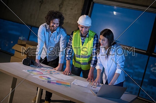 young team of business people in group, architect and engineer on construction site checking documents and business workflow using laptop computer in new startup office