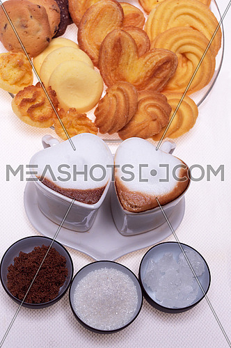 valentine day heart shaped espresso coffee cappuccino cups with assortment of pastry mignon  and white brown and rock sugar over white