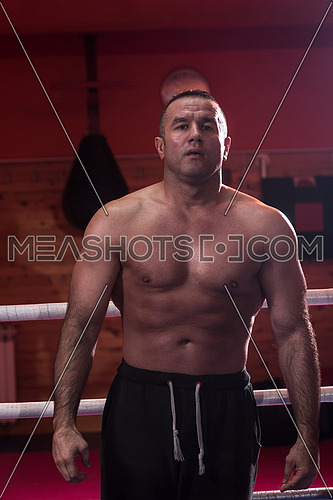 portrait of muscular professional kickboxer who standing in the ring while training for the fight