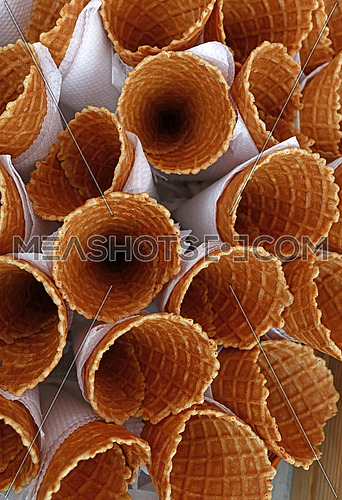 Several empty fresh wafer ice cream cone cornet cups with white paper napkins, close up, elevated high angle top view, directly above