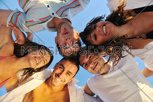 happy young friends group team huging have fun and celebrate  on the beach at the sunset