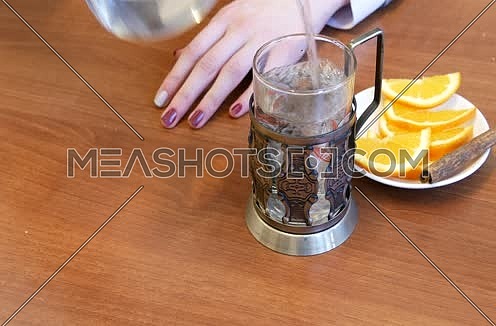 Green tea. Girl pouring tea into a glass cup.
