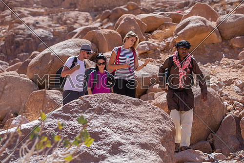 Long shot for group of tourists walking on big rocks explore Sinai Mountain for wadi Freij at day. for group of tourists walking with bedouin guide to explore Sinai Mountain for wadi Freij at day.