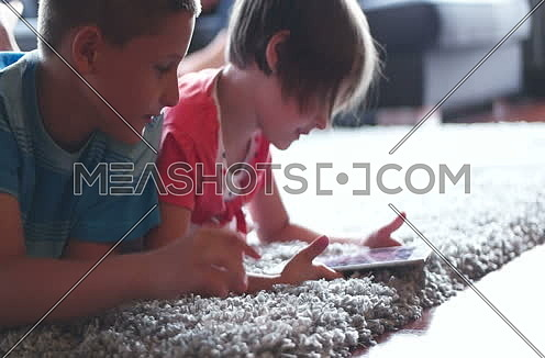 children using tablet at home on carpet
