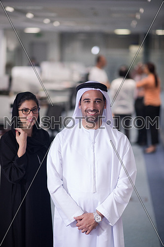 arabian famale and male business people standing as team in modern office with group of people in background