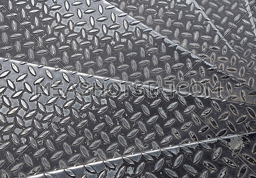 Black painted industrial anti slip embossed metal steel plate steps of staircase with diagonal bumps of diamond pattern texture, background, close up