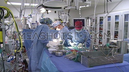 Pan left long shot of operating room while medical team performing surgery