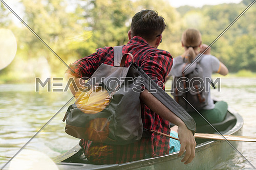 Couple adventurous explorer friends are canoeing in a wild river surrounded by the  beautiful nature