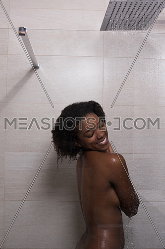 Woman in the shower,beautiful black young female showering under refreshing water, healthy lifestyle, enjoying time in luxury spa resort