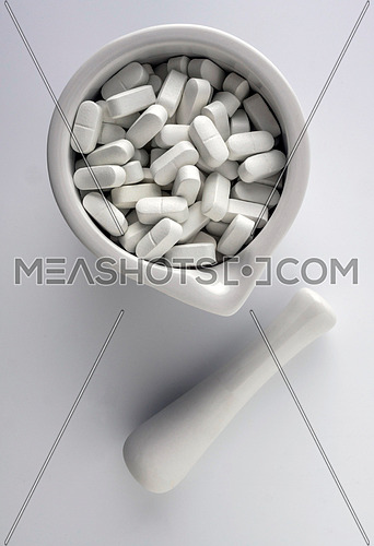 Several pills inside white mortar, conceptual image
