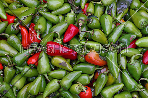 Green hot jalapeno and red chili peppers for sale at retail farmers market stall display, close up background pattern, elevated top view