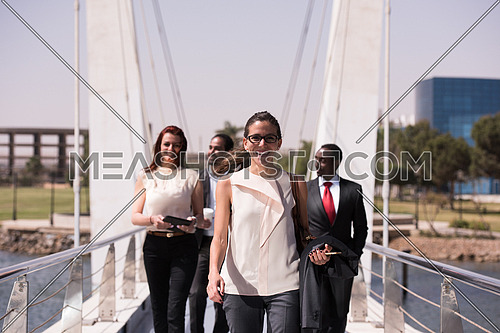 young multi ethnic business people group walking across modern bridge and drink first morning coffee