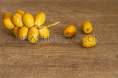Yellow dates arranged on a wooden table