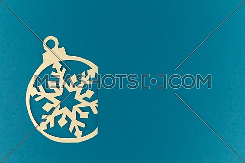 Christmas and New Year background. Small paper cut ball inserted into the slot on blue background. Holiday postcard concept with copy space