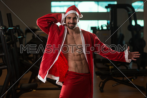 Young Muscled Man In Santa Claus Outfit Posing In A Fitness Center Gym