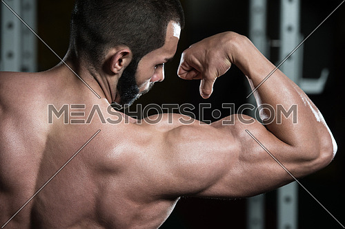 Portrait Of A Young Fit Man Flexing Front Biceps Pose - Muscular Athletic Bodybuilder Fitness Model Posing After Exercises