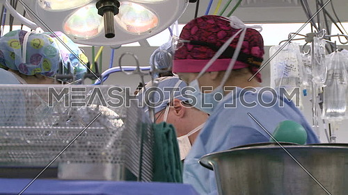 Low angel shot for medical team performing surgery and surgical tray in foreground