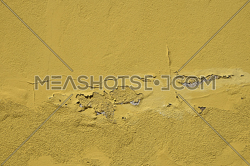 Vintage flakes of old faded yellow paint over abandoned grey concrete wall
