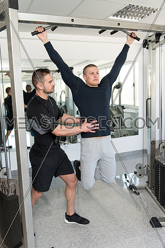Personal Trainer Showing Young Man How To Train Pull Ups - Chin-Ups In The Gym