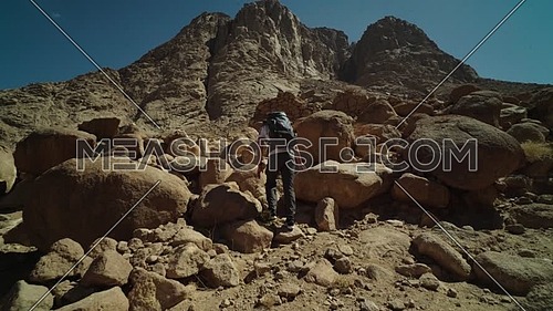 Follow shot for a male tourist wearing a grey travel backpack explore Sinai Mountain for wadi Freij at day.