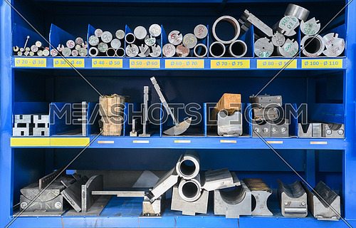 pipes, metal pieces, and various metal parts for a CNC machine standing on a shelf. High quality photo