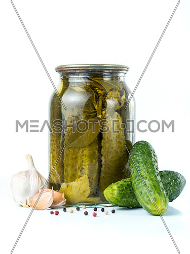 Pickled cucumbers isolated. Pickles in glass jar with garlic and peppercorn isolated on white background. Salted cucumber in jar isolated