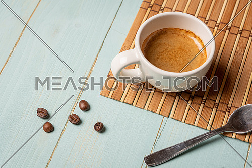 White cup of coffee,teaspoon and coffee bean on green background. Copy space.
