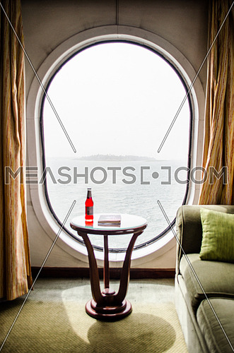 A big window in a ship and a coach in a ship room