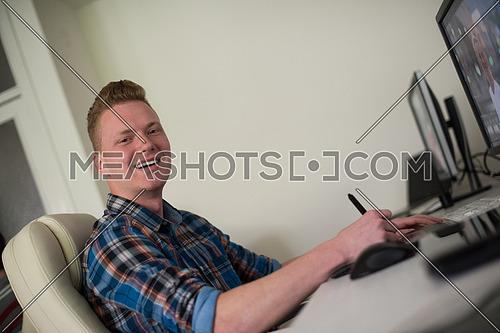 Young graphic designer working on a digital tablet and a computer