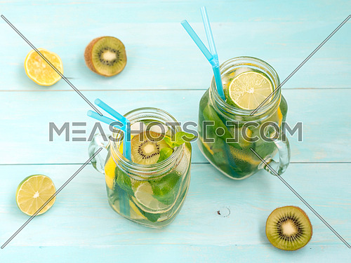 Cold homemade lemonade with fresh lemon, lime, kiwi and mint in mason jar. Summer drink on soft blue wooden background
