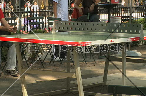 Medium shot for an adult male playing Ping pong in the park in new York City at day.