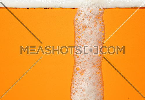 Close up background texture of lager beer with bubbles and froth, pouring in glass, low angle, side view