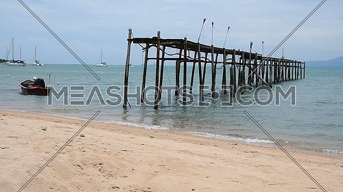 Old ruined wooden pier and boats on sand sea beach, sunny day at Koh Samui island, Thailand, low angle view