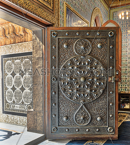 Opened wooden aged door with ornate bronzed floral patterns at the mosque of The Manial Palace of Prince Mohammed Ali Tewfik, Cairo, Egypt