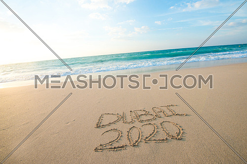 in the picture at the beach  written on the sand Dubai 2020
