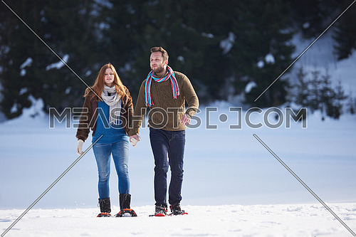 happy young  couple having fun and walking in snow shoes. Romantic winter relaxation scene