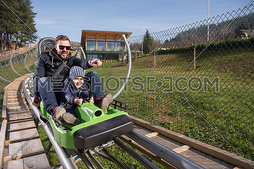 Excited father and son enjoys driving on alpine coaster