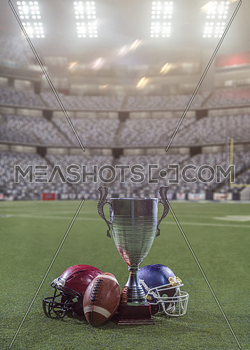 closeup shot of american football,helmets and trophy on grass field at modern stadium with flares and lights at night