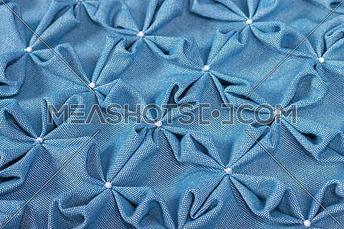 Close up background texture of soft blue textile puffs for Canadian smocking upholstery decoration with beads