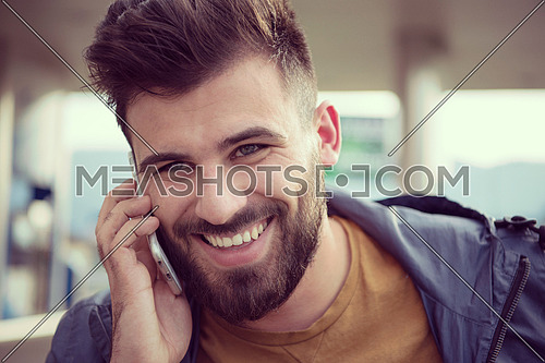handsome young casual business man with beard using cell phone and smile outdoor on city street