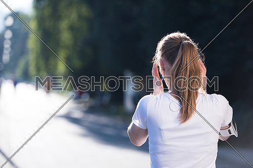 jogging woman setting music and running route on  smart phone putting  earphones before morning run